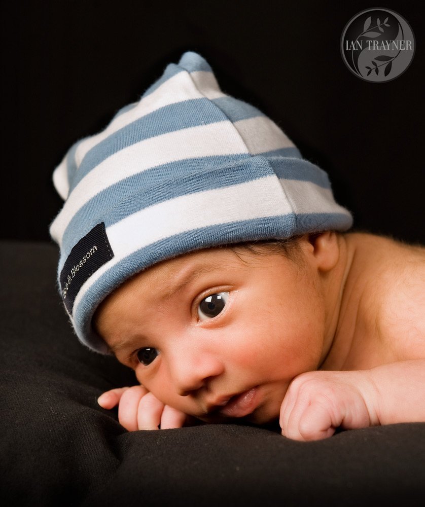 Cute little baby looking up. Blue and white hat on his head. Baby photo shoot.