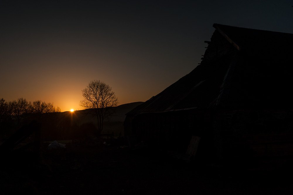 The Magic of Light. The sun rises in the Welsh hills. Barn silhouetted agains the morning sky.